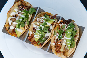 Overhead view of three meat tacos with all the toppings  perfectly prepared on the grill with chicken and steak.