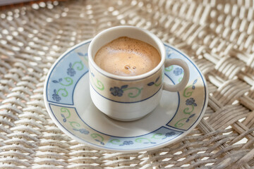 cup of coffee on a wicker table early in the morning