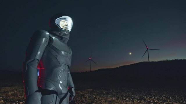 Space man. Night view at the man astronaut walking on the empty field and admiring the beautiful earth with windmills at the background. Man looking at the sides. Futuristic, galaxy, interstellar