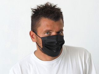 man in a black protective mask with tousled hair.