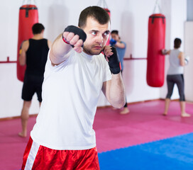 strong sportsman in the boxing hall practicing boxing punches during training