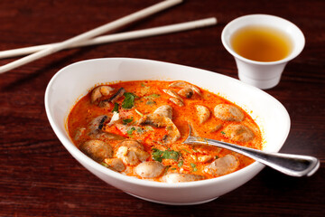 Thai Tom Kha Kai Soup in a white bowl on a dark wooden table