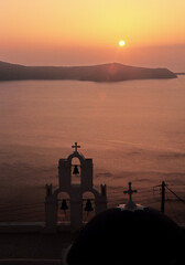 View of Santorini blue domed church and Church bells under sunset in Santorini, Greece. 