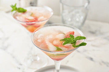 Glasses of tasty strawberry mojito on light background