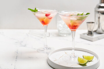 Glasses of fresh strawberry mojito on light background