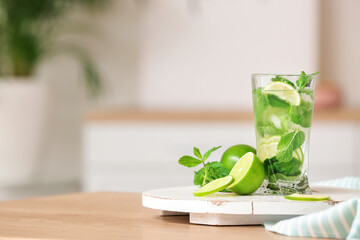 Glass of fresh mojito on table in kitchen
