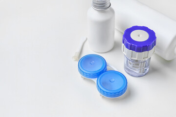 Container with contact lenses and solutions on white background