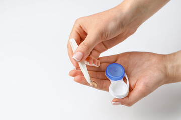 Woman holding tweezers with contact lens and container, closeup