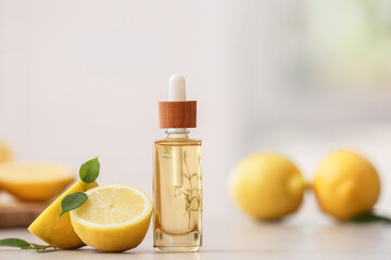 Bottle with lemon essential oil on blurred background