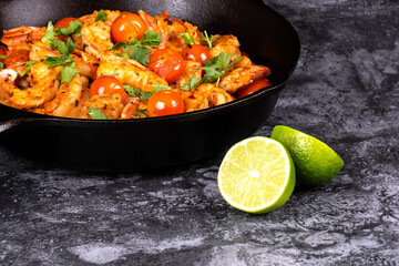 Closeup of a Cast Iron Pan Filled with Cooked Shrimps, Cherry Tomatoes, White Beans, Garnished with Cilantro