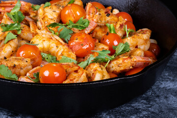 Closeup of a Cast Iron Pan Filled with Cooked Shrimps, Cherry Tomatoes, White Beans, Garnished with Cilantro