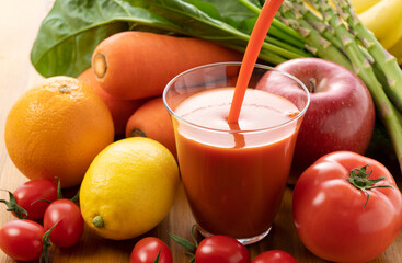 Pour vegetable juice into a glass. Many kinds of vegetables behind