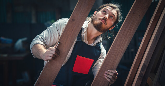 carpenter in wood workshop selecting wooden frame for his workwood