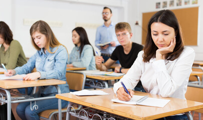 concentrated young schoolgirl is sitting test and answer about task in the classroom.