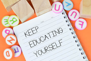 Selective focus of alphabet erasers, wooden cubes and notebook written with text KEEP EDUCATING...