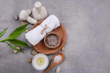 spa composition with green bamboo  and towel, salt in wooden bowl ,stones on grey background