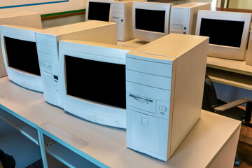 old CRT computer monitors and towers in classroom.