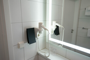 Hair dryer in bathroom at the front of mirror in the luxury hotel