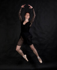 Fototapeta na wymiar Beautiful dancer studio portrait jumping on black background.