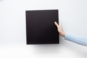 Hands hold a black sheet. Empty space for the label.