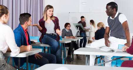 Positive adult students communicating during recess between lectures in auditorium