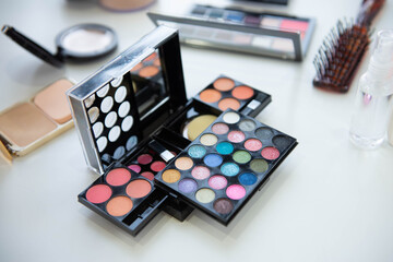 Female decorative cosmetic with lipstick and eyeshadow palette on the table