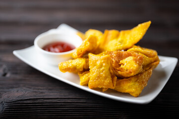 Deep fired Chinese Thai style wonton with minced pork and sweet and sour sauce in ceramic dish.