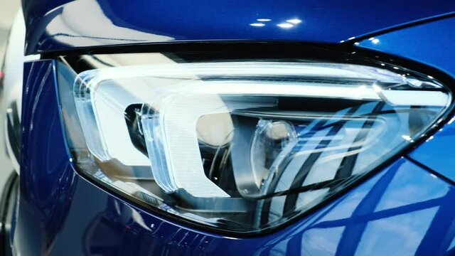 Close-up of the headlight of a new blue car in the showroom. Modern laser headlights. Led lights. Xenon. Bixenon. Side panoramic view