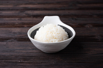 Bowl of boiled rice served on wooden table,