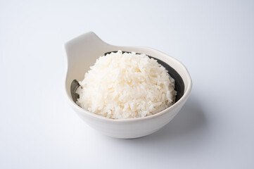 Bowl of boiled rice served on wooden table,