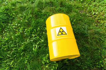 Radiation hazard symbol sign.  The nuclear sign on a yellow metal barrel on the green grass. Radioactive waste
