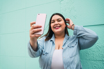 Young plus size woman taking selfies with phone.