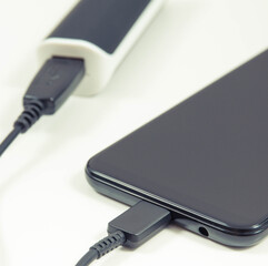 Smartphone with connected plug of powerbank. Telephone charging