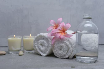 Poster Spa setting Composition with towel, spa stones and candles ,pink frangipani on gray background © Mee Ting
