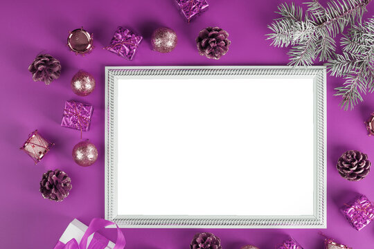 Frame with empty white space with Christmas decorations and gifts on pink background.