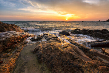 Beautiful tropical sea beach at sunrise, waves and rock on shore