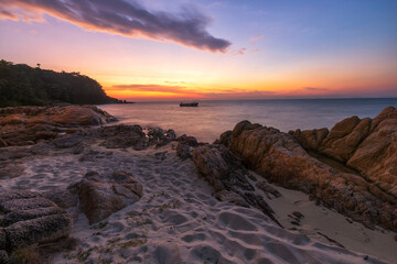 Beautiful tropical sea beach at sunset. Silky waves and rock on shore