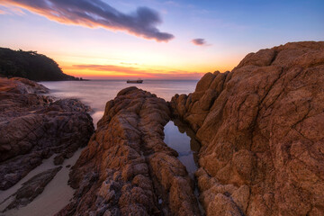 Beautiful tropical sea beach at sunset. Silky waves and rock on shore