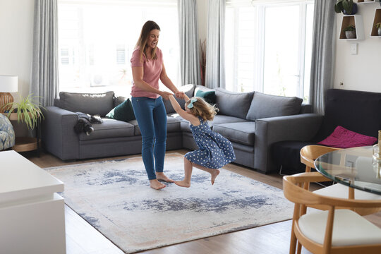 Caucasian Mother And Daughter Having Fun Dancing In Living Room