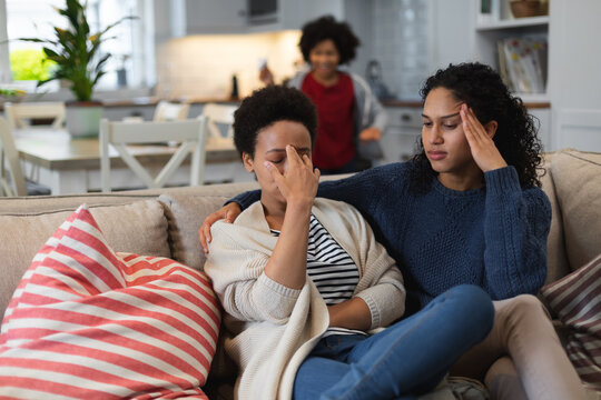 Upset mixed race lesbian sitting on couch