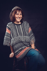 Cheerful 40 years old woman dressed in jeans and poncho studio portrait