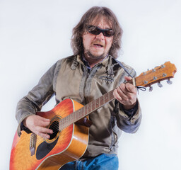 Mature musician plays acoustic guitar studio portrait.
