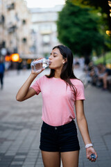 Beautiful young girl drinks with a bottle of water