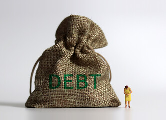 A bundle bearing the word DEBT a bundle and a miniature woman standing with her head down. The...
