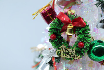 Focus and soft lens Christmas tree decorated with colored balls and gift boxes with Christmas wreath and silver bells on white background.