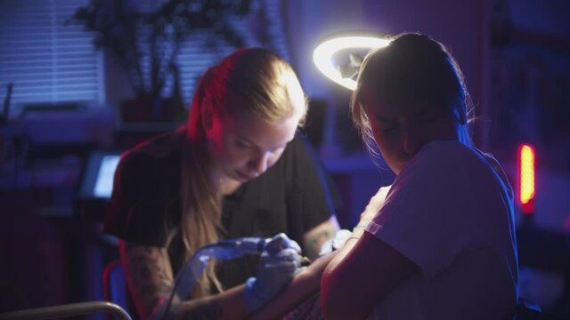 Tattoo session - young woman getting a minimalistic tattoo on her arm - feeling pain