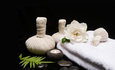 Fototapeta na wymiar beautiful spa concept of white gardenia flower on towel and green fern ,candle ,herbal ball on pile of black zen stones 