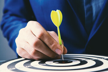 Close up hand of business man holding dart on target