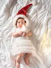 Funny baby girl lying on the bed in Christmas clothes