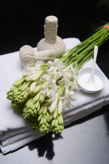 spa concept with bunch of tuberose flowers ,buds on towel, cream in bowl and herbal, ball,

